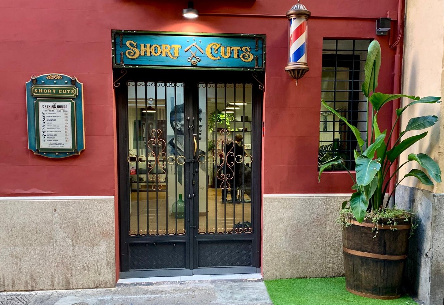 Short Cuts Barbershop street entrance with red facade and barber pole